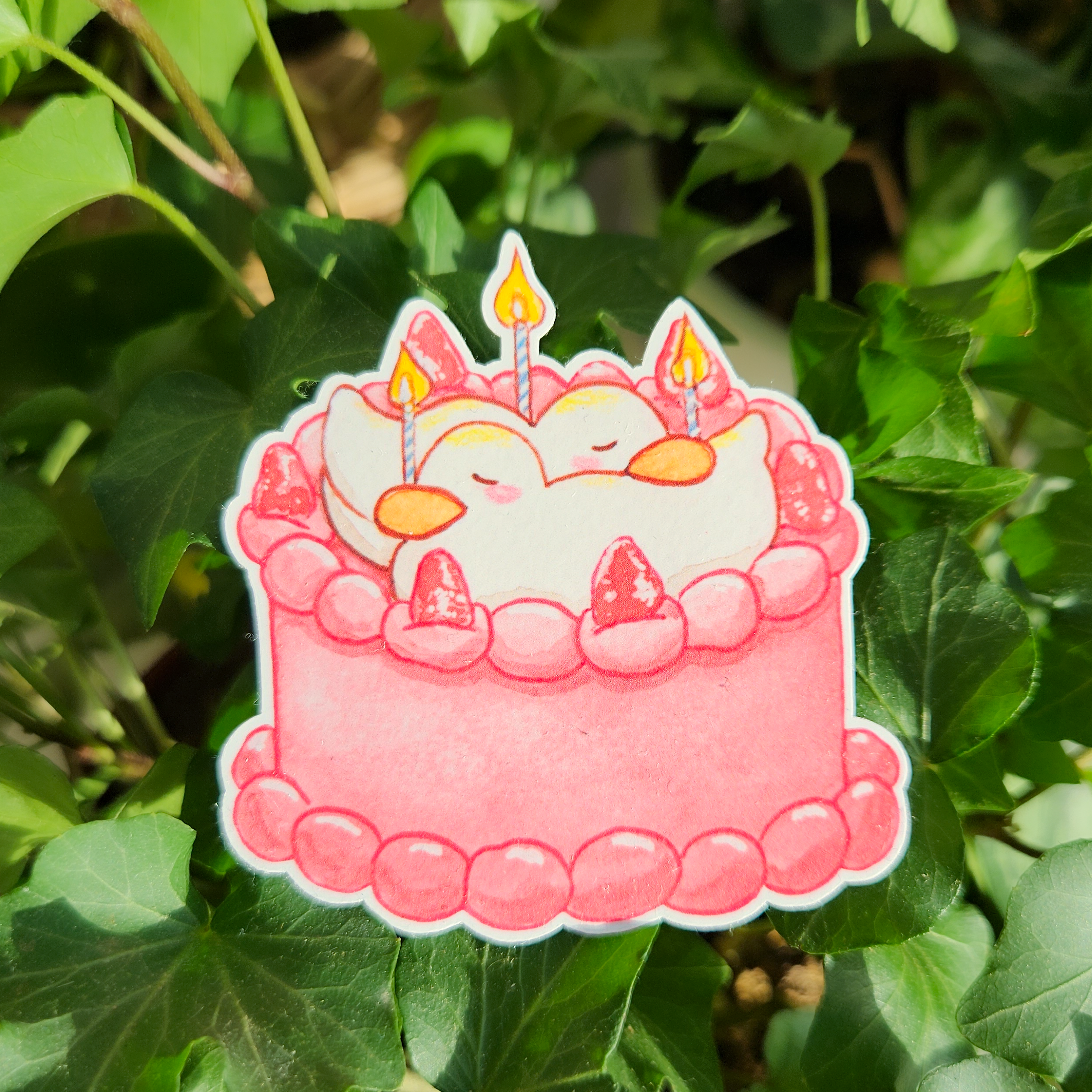 Sticker of a pink cake with candles with cute ducks on top
