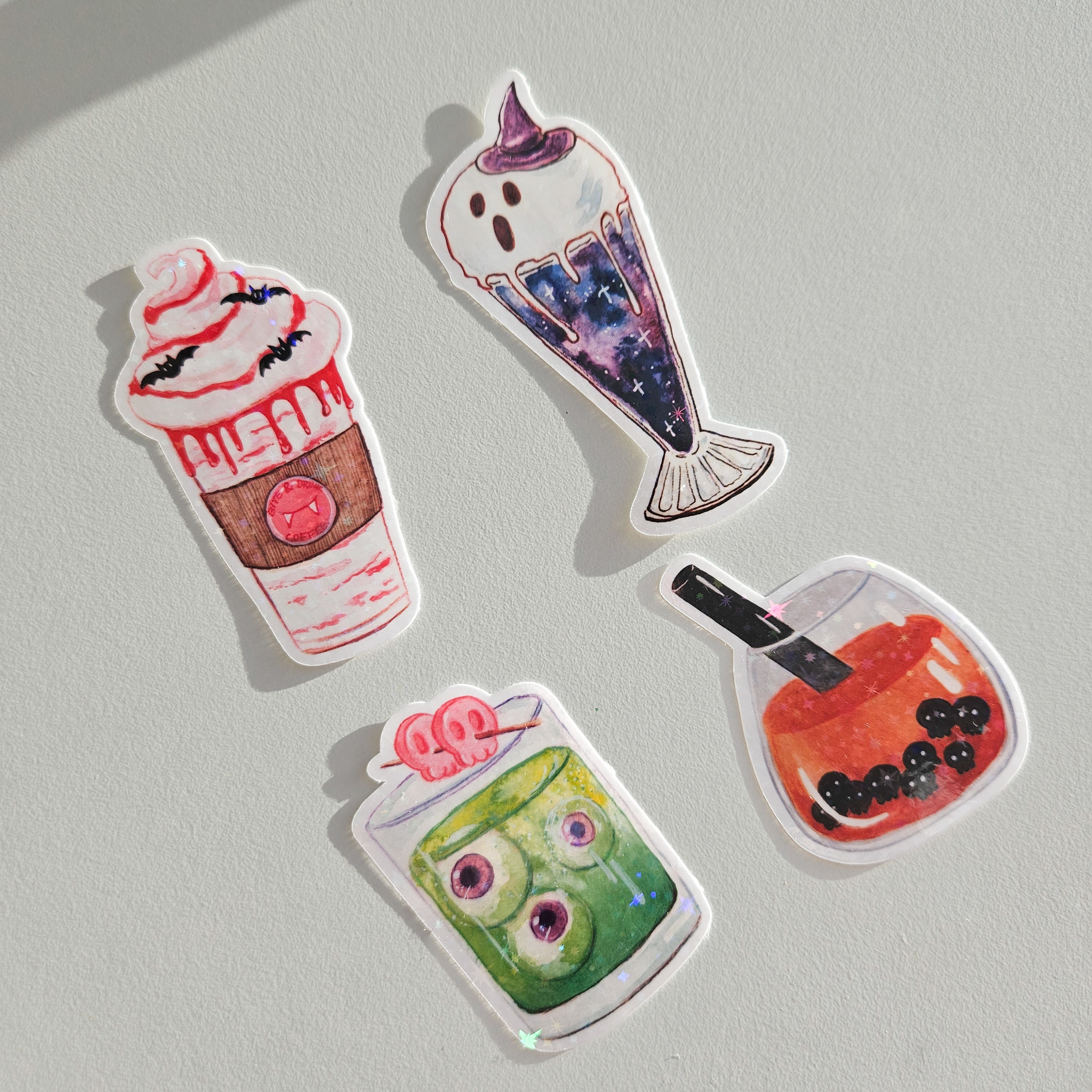 Four colorful halloween food-themed drinks stickers on a white table.