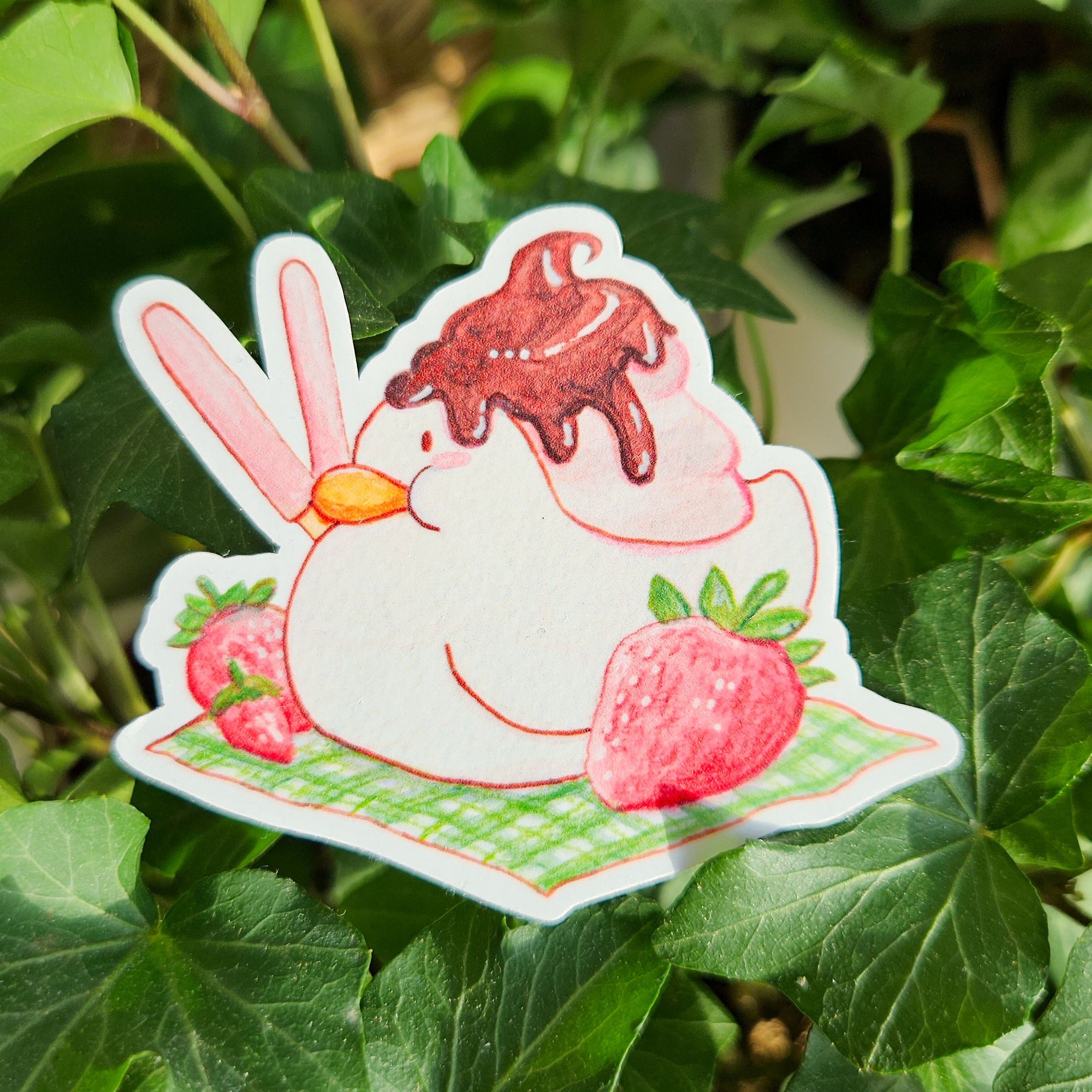 Sundae duck sticker,, duck with cream and melted chocolate on top, with pocky sticks and strawberries on a picnic blanket